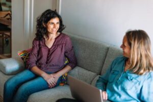 Two friends sit on couch and talk about psychotherapy programs